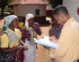 Man with a clipboard talking to woman in a village